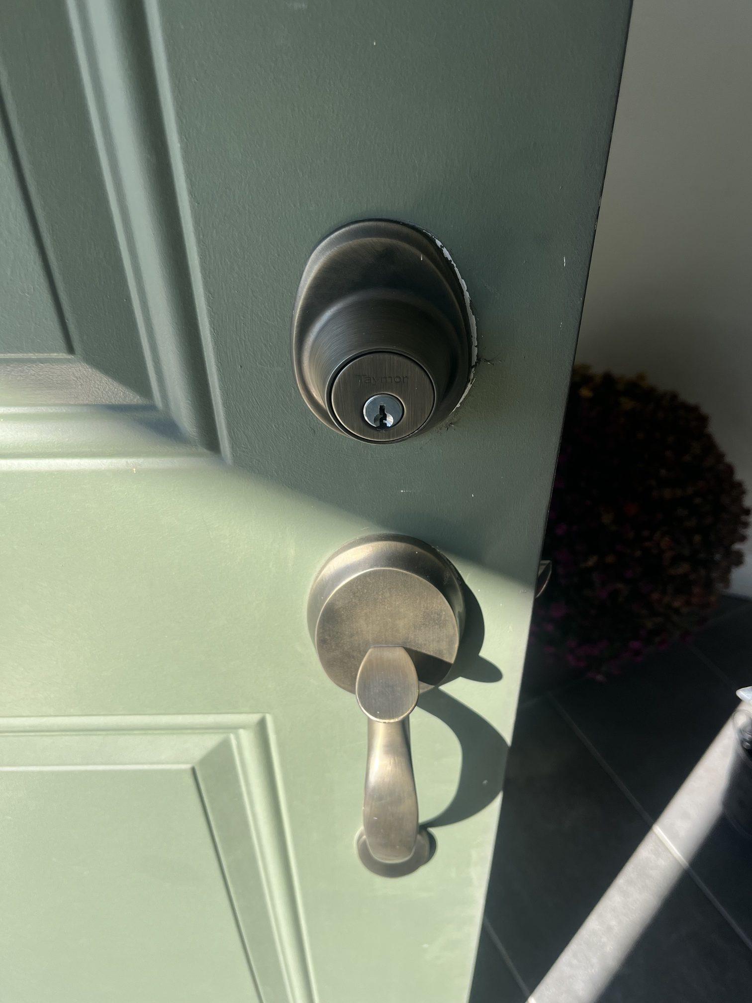Traditional Taymor keyed deadbolt on a residential front door before smart lock installation