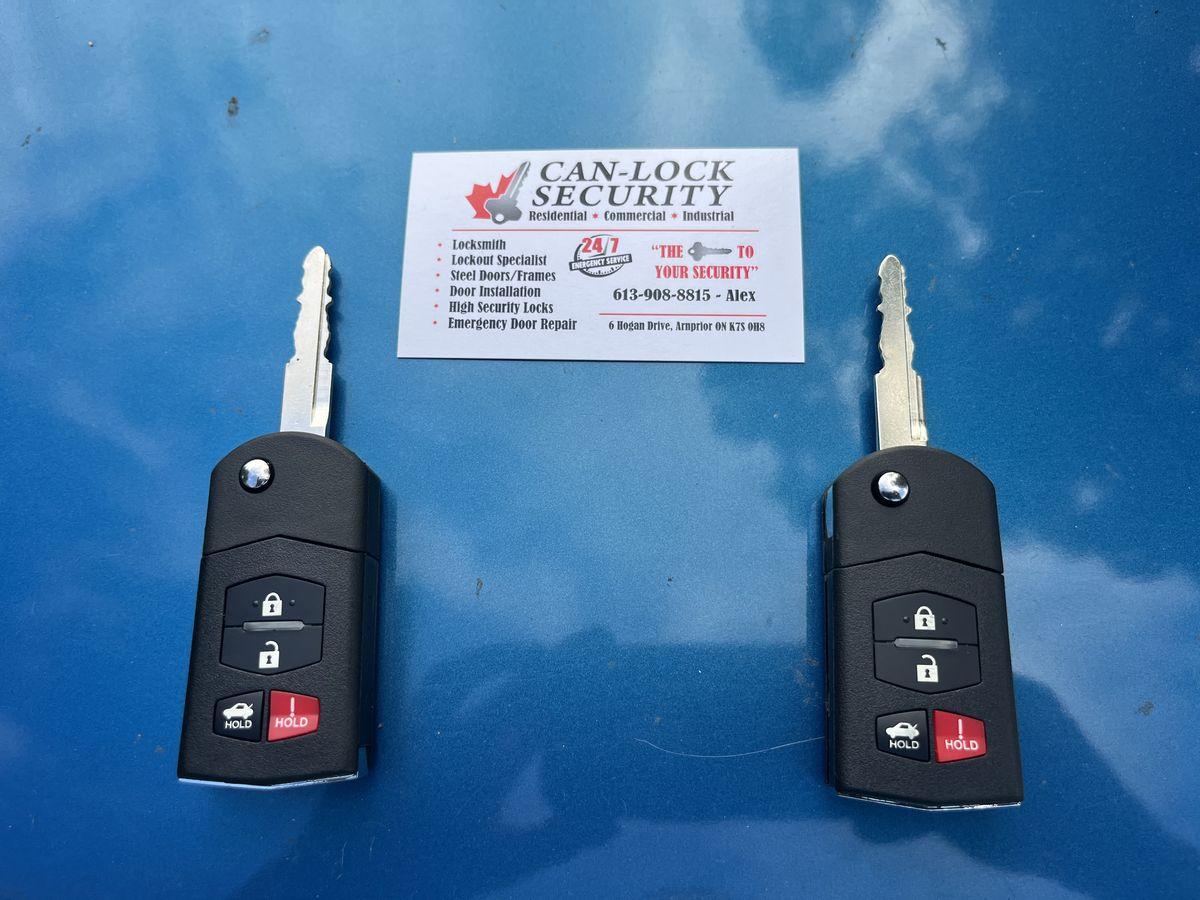 Duplicated car key fobs next to a Can-Lock Security business card