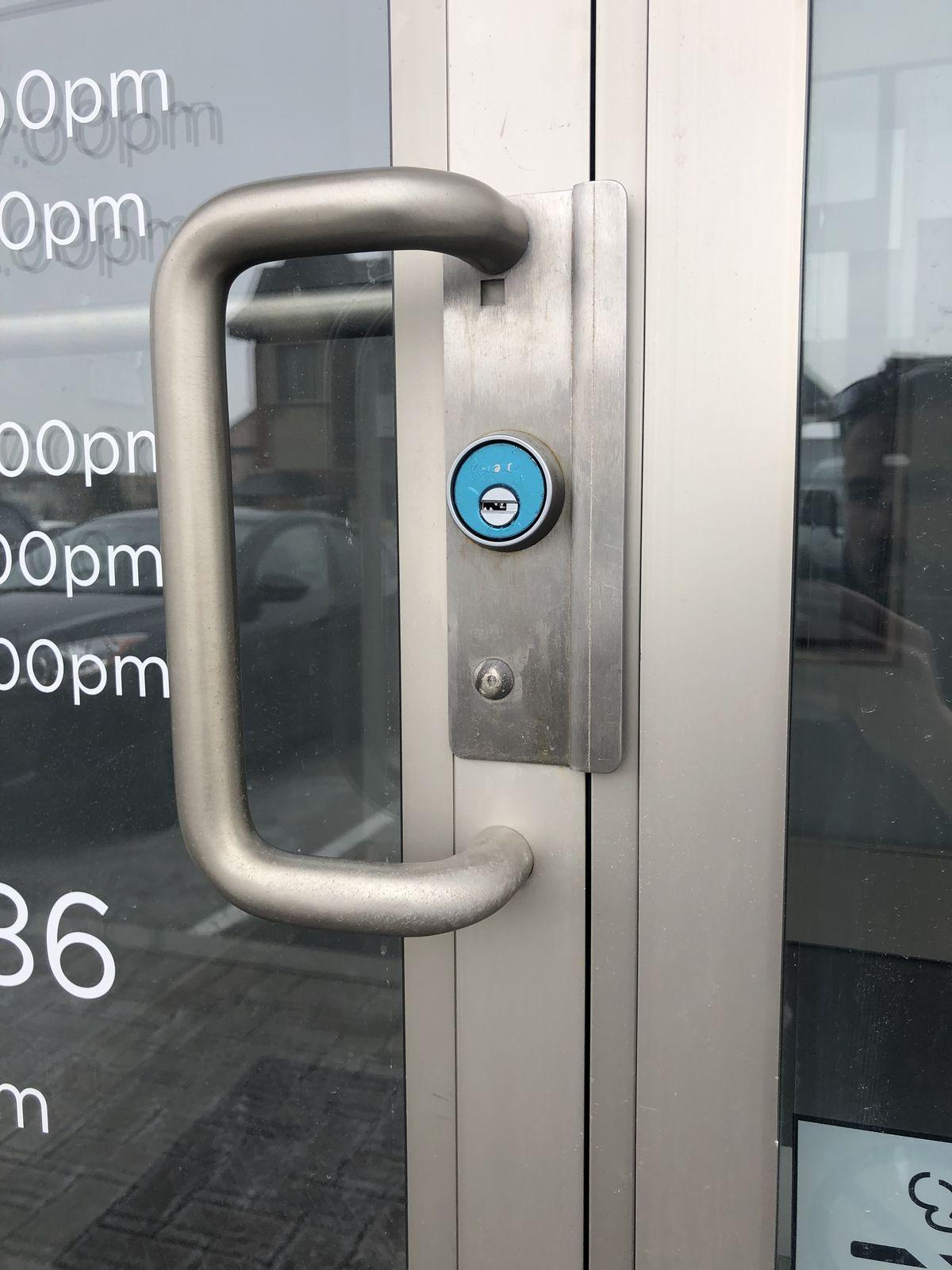 Commercial storefront pull handle with keyed cylinder on a glass door