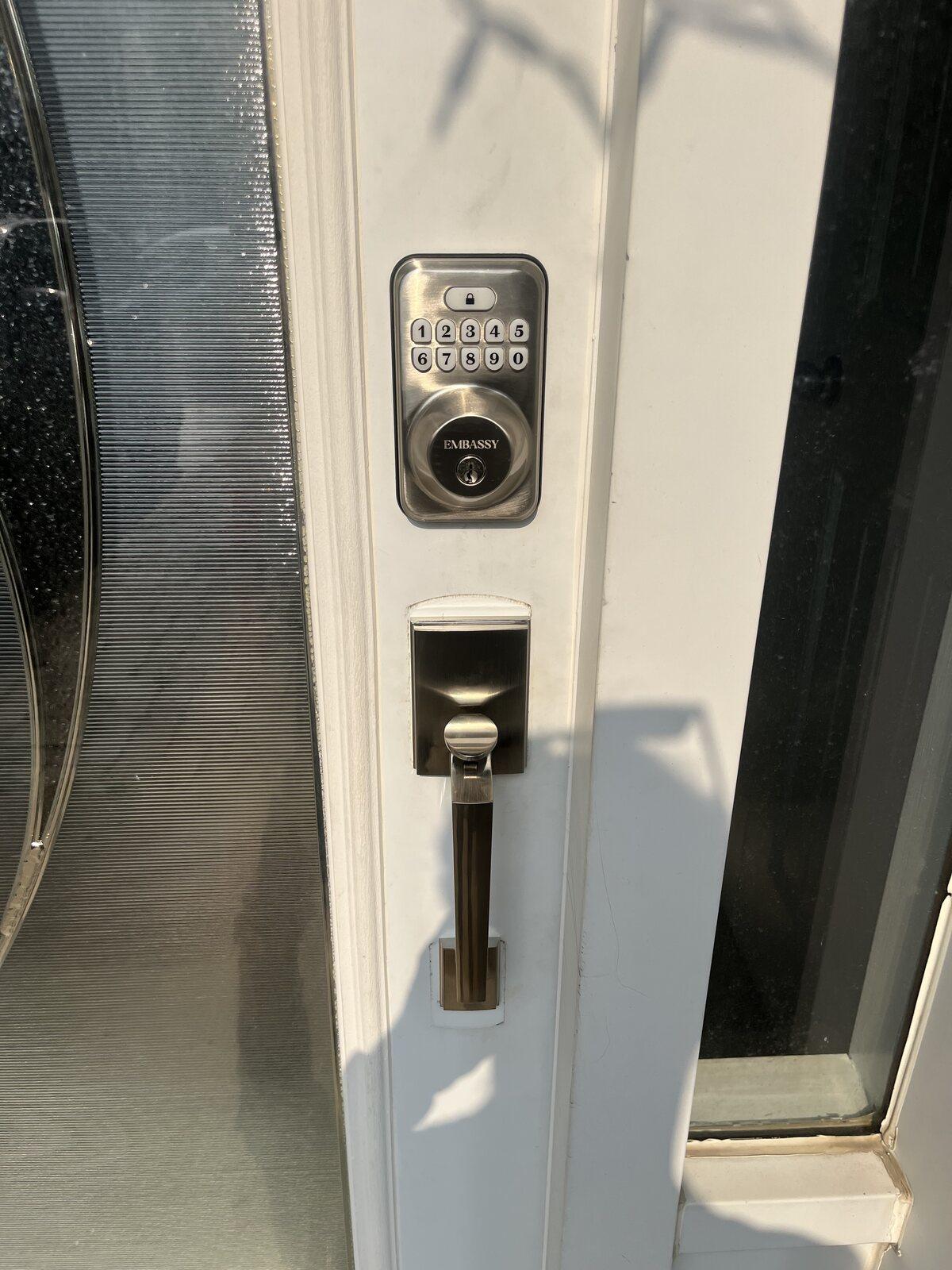Keypad deadbolt installed above a matching handleset on a white residential front door
