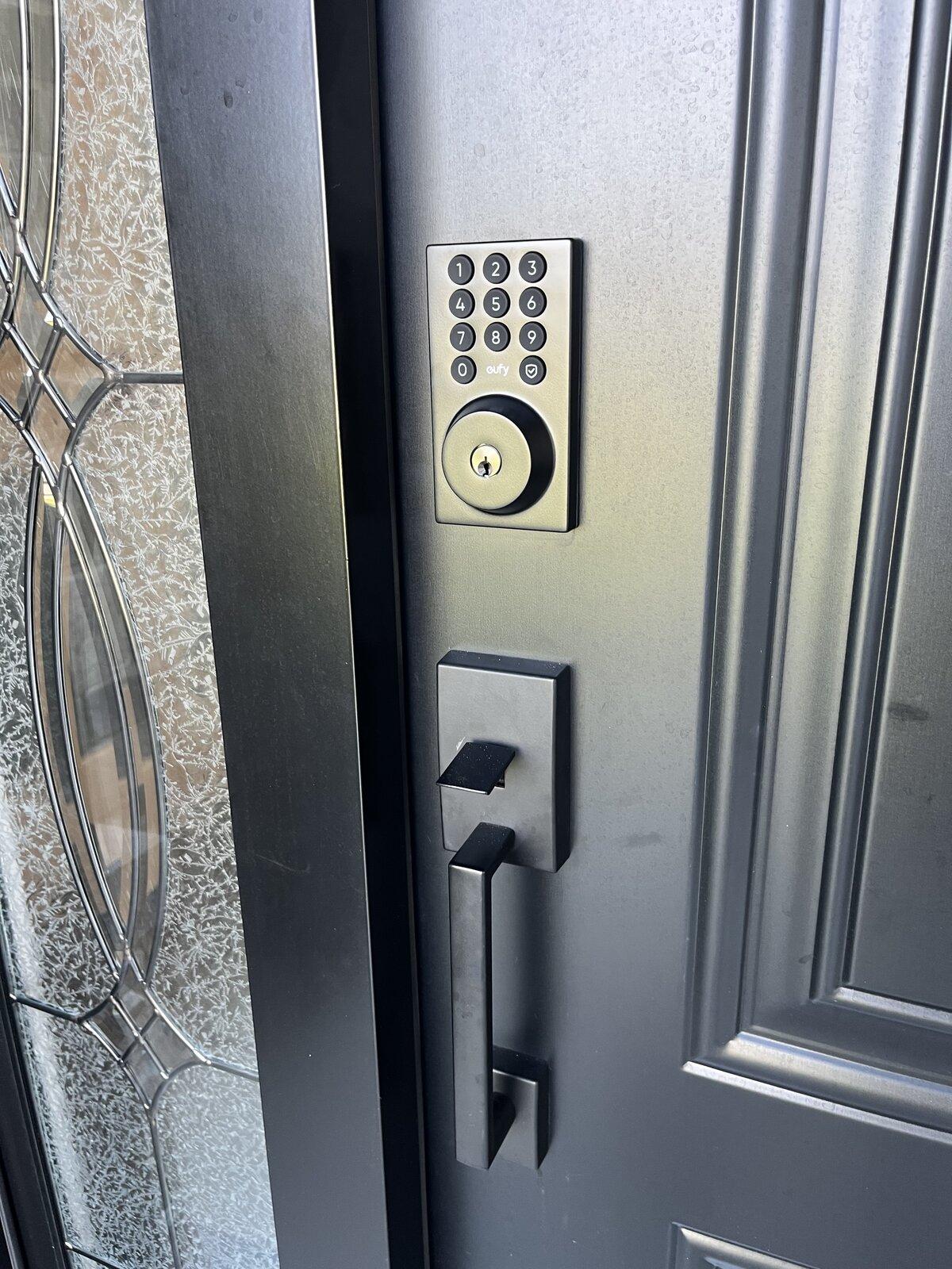 Matte black Eufy keypad smart deadbolt installed above a matching handleset